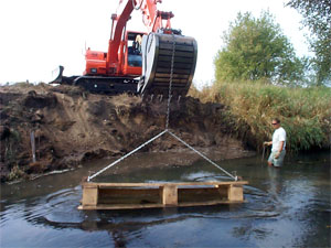 [Photo: Lunker structure being placed in riverbank.]