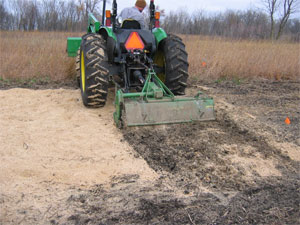 [Photo: Tractor tilling sawdust into soil.]