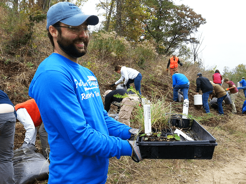 Adam Flett holds a tray of plants at a stewardship event